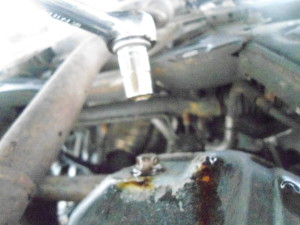 About to remove the oil drain pan bolt with the socket wrench